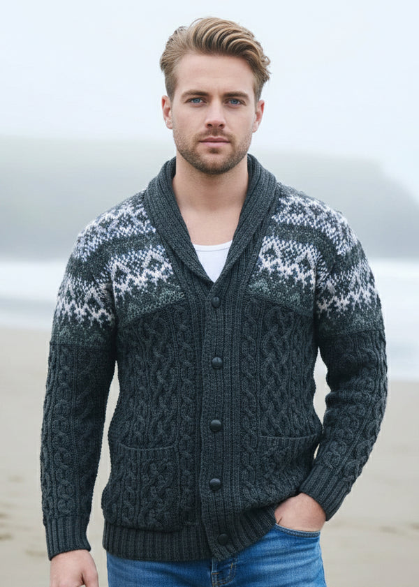 Man wearing a patterned cardigan standing outdoors with a body of water in the background