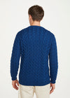 Man wearing a blue cable knit aran sweater on a white background