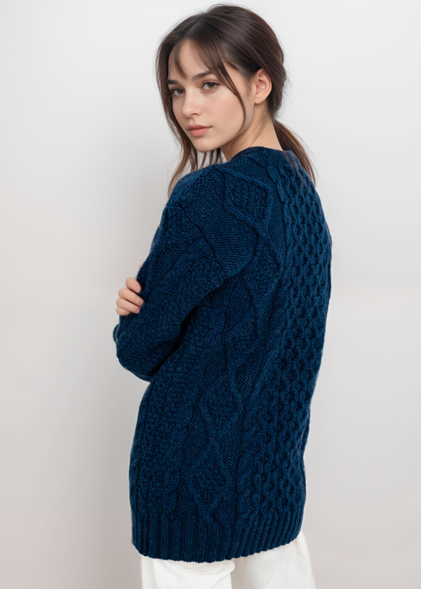 Woman wearing a dark blue cable knit sweater against a white background