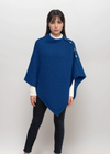 Woman wearing a blue aran poncho on a white background