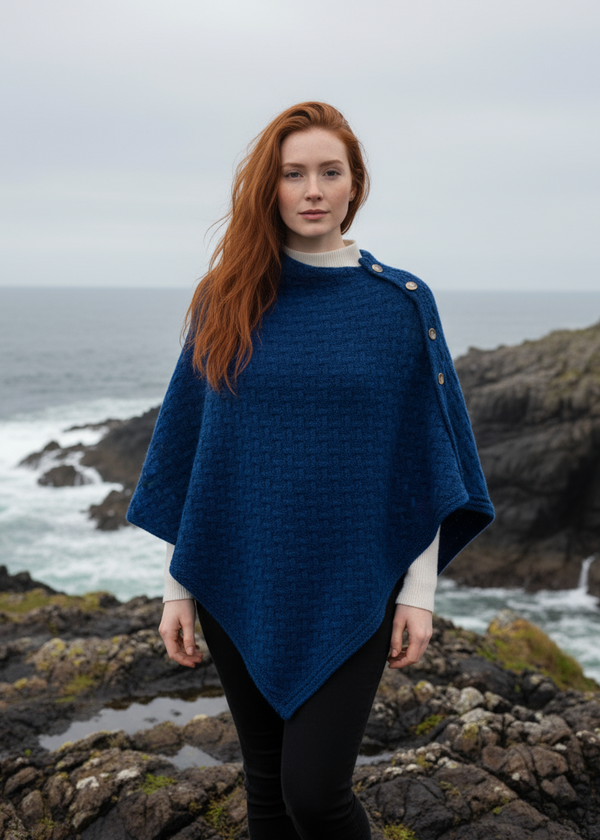 Woman wearing a blue aran poncho on a white background