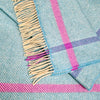 Close-up of a plaid fabric with pink and blue stripes and fringed edge.