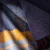 Close-up of a plaid fabric with blue, yellow, and purple colors.