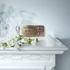 Decorative plaque with a cross on a white surface with flowers and a vase.