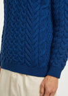 Close-up of a blue cable knit sweater on a plain background