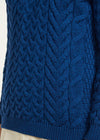 Blue knitted sweater with cable pattern worn by a person, brand 'Aran Woollen Mills'