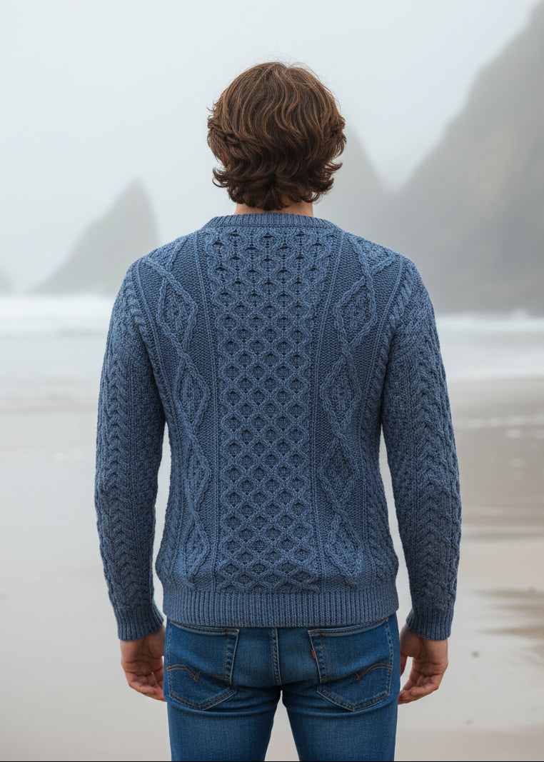 Man wearing a blue knitted aran on a beach