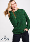 Woman wearing a green sweater with 'Aran Woollen Mills' branding on a white background