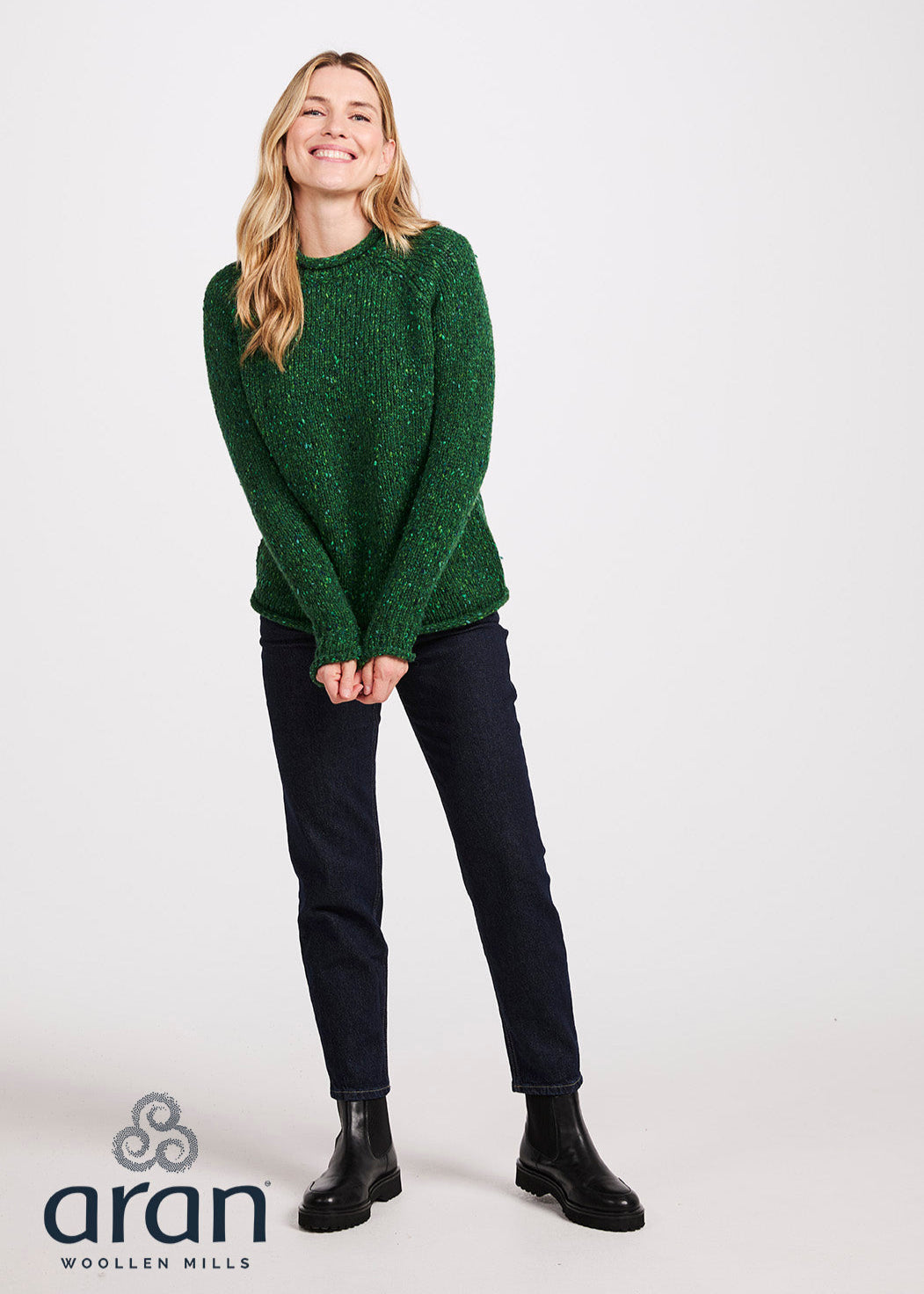 Woman wearing a green sweater with 'Aran Woollen Mills' branding on a white background