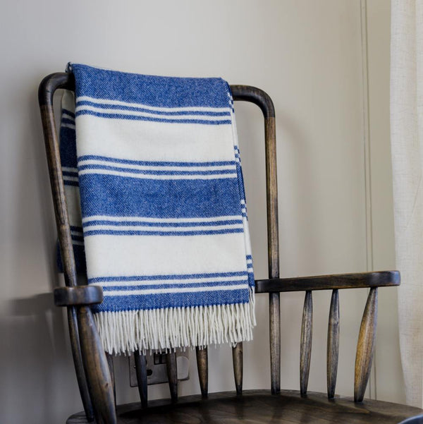 Blue and white striped blanket draped over a wooden chair against a neutral wall.