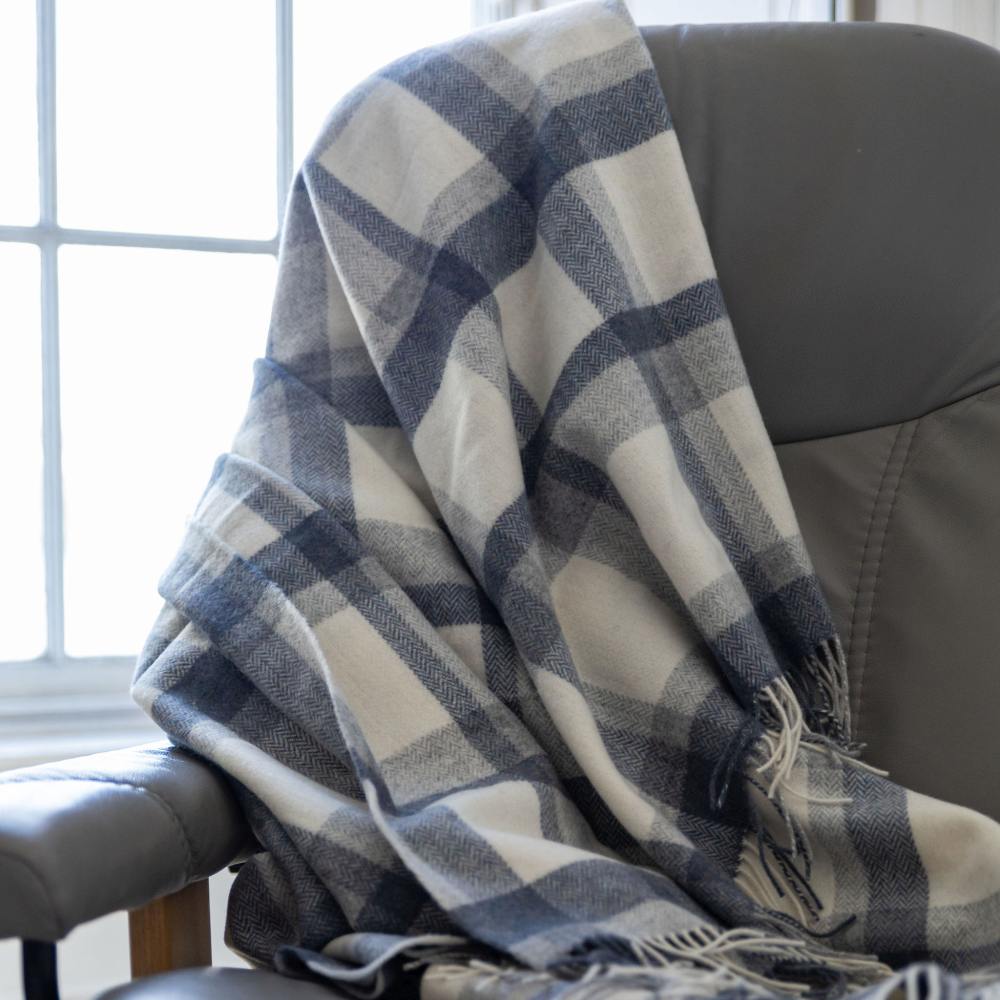 Plaid blanket draped over a gray chair by a window