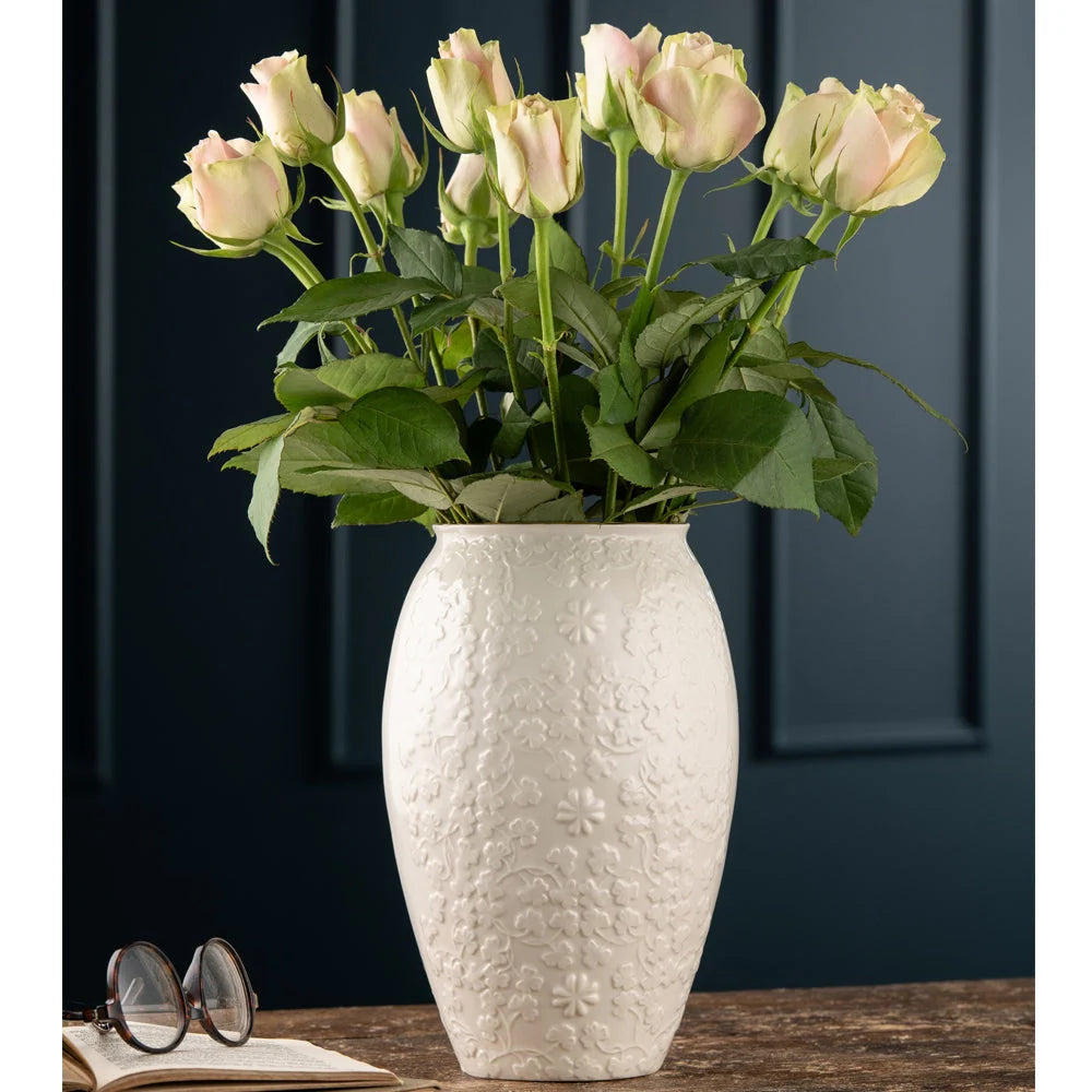 White textured vase with pink roses on a wooden surface against a dark background