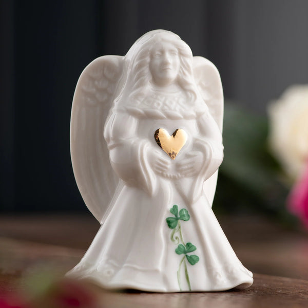 White angel figurine holding a gold heart with a blurred background