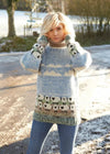 Person wearing a patterned sweater with sheep design outdoors on a snowy day.