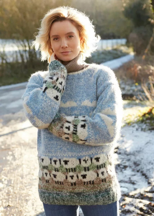 Woman wearing a patterned sweater with sheep design outdoors on a snowy day.
