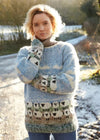 Woman wearing a patterned sweater with sheep design outdoors on a snowy day.