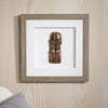 Framed artwork of a bronze sculpture on a wooden wall