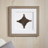 Framed decorative wall art with a geometric design on a wooden wall.