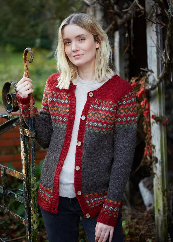 Woman wearing a red and gray patterned cardigan standing outdoors.