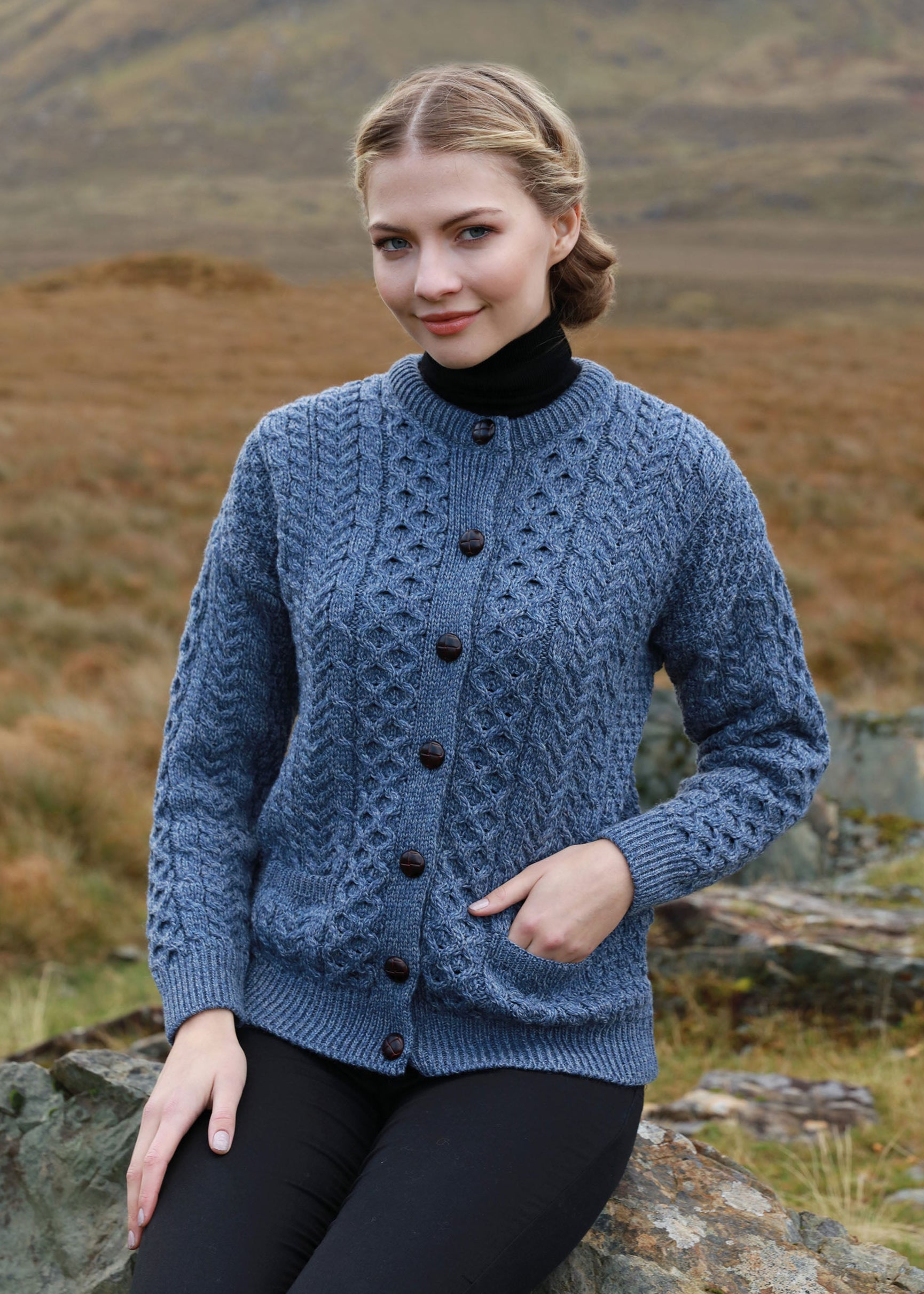 Woman wearing a aran blue knitted sweater with a mountainous background