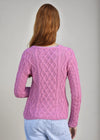 Person wearing a pink knitted sweater on a gray background