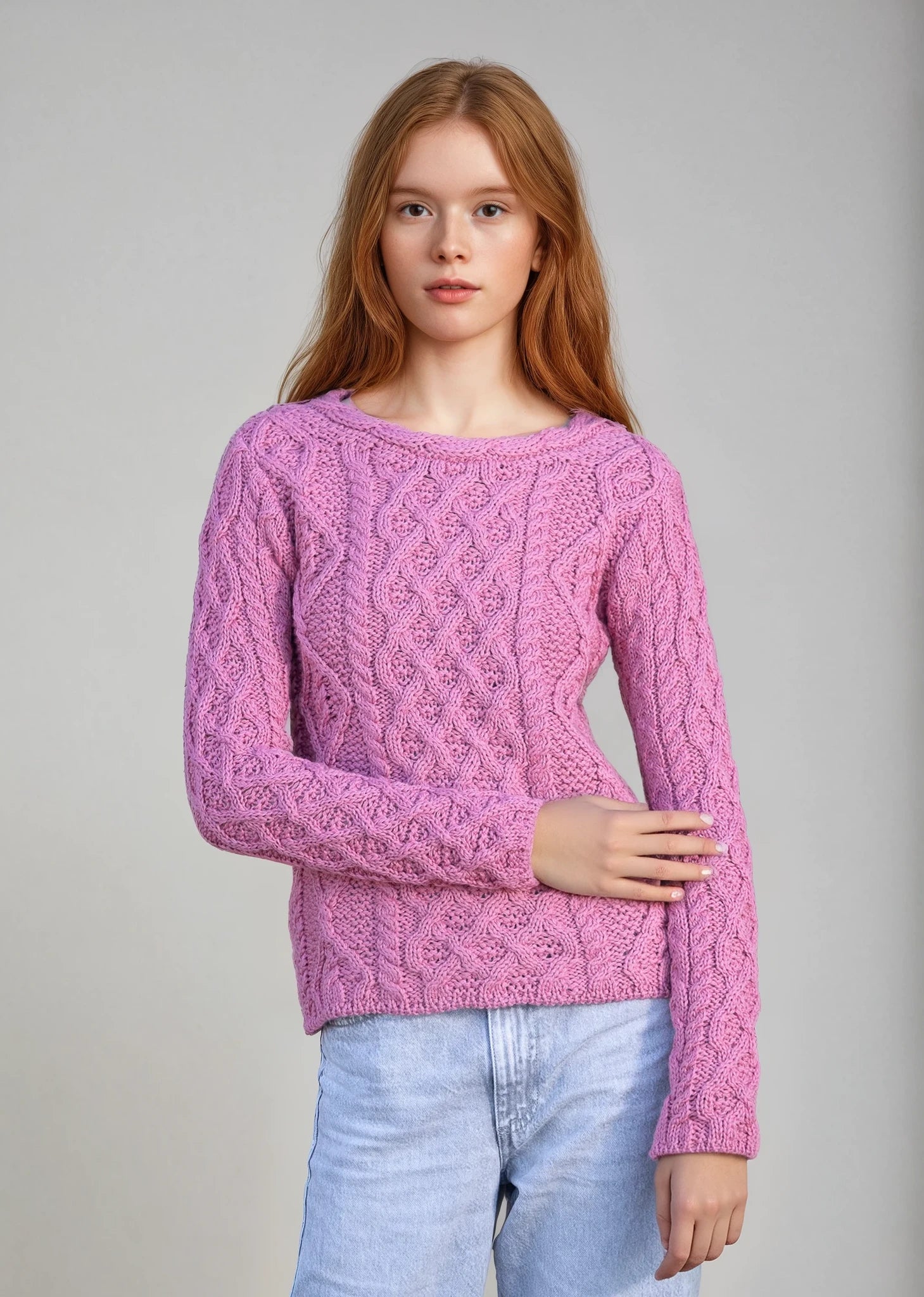 Woman wearing a pink knitted sweater against a gray background