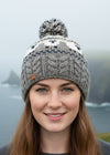 Knitted beanie with a sheep pattern and pom-pom on a white background