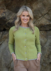 Woman wearing a green cardigan standing against a rocky background
