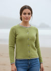 Woman wearing a green cardigan standing against a rocky background