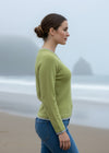Woman wearing a green sweater standing against a rocky background