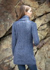 Woman wearing a blue knitted cardigan standing against a rocky background