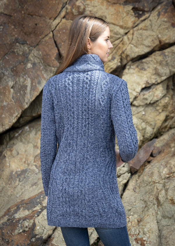 Woman wearing a blue knitted cardigan standing against a rocky background