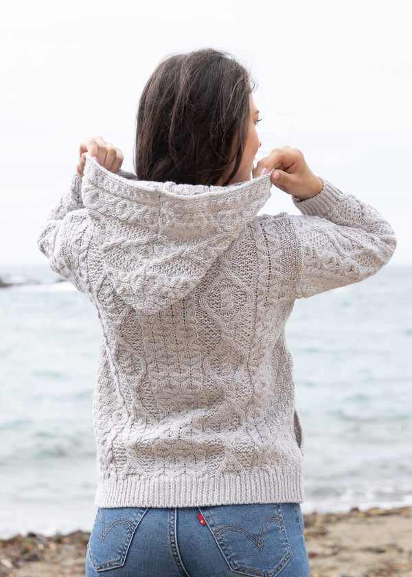 Person wearing a textured beige hoodie by the water