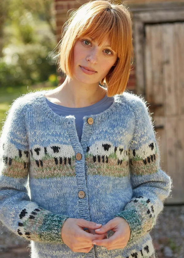 Woman wearing a blue knitted cardigan with sheep pattern outdoors