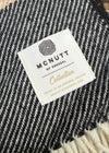 Close-up of a black and white textured woven blanket with a white brand label reading 'MCNUTT OF DONEGAL Collection'.