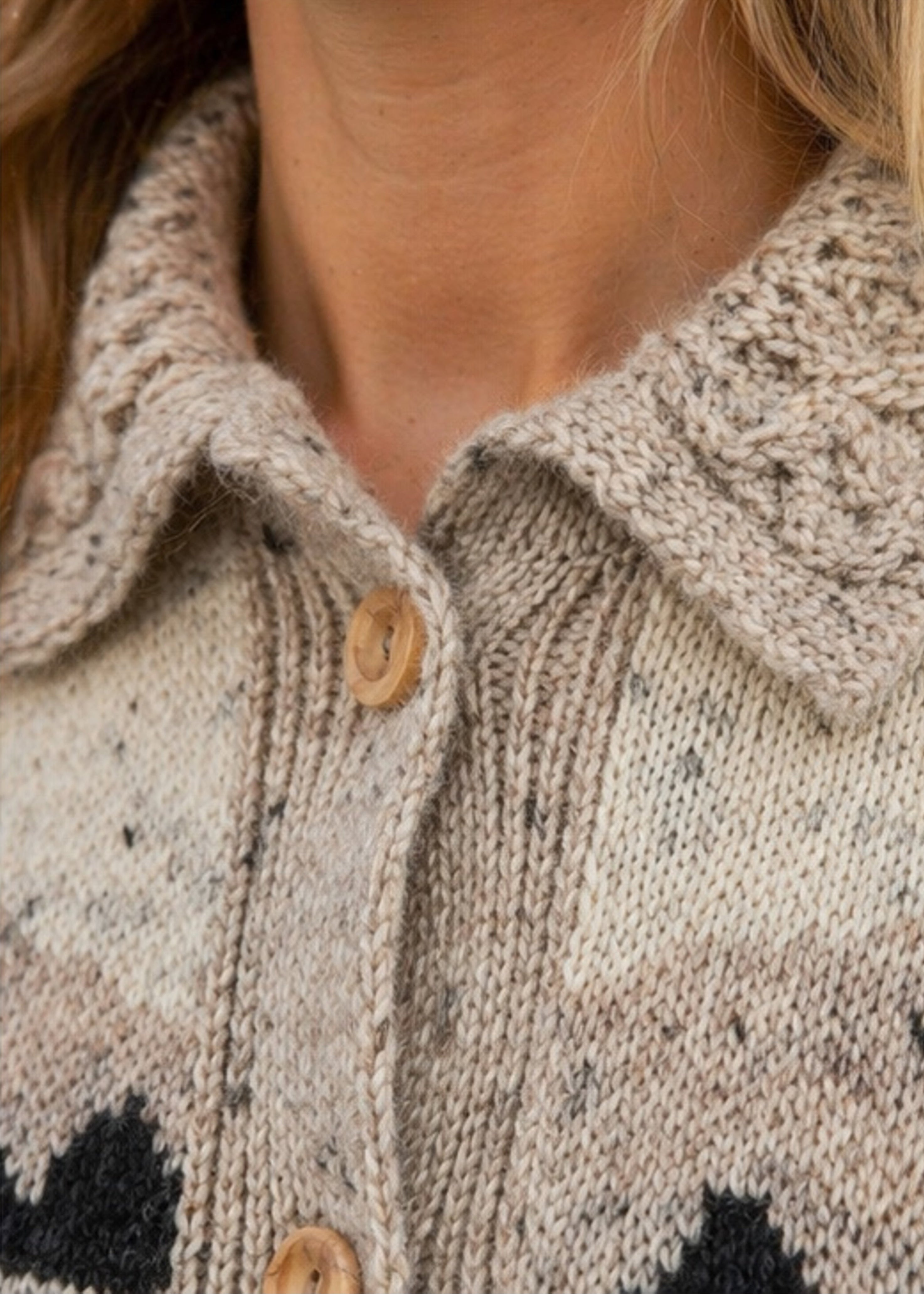 Close-up of a person wearing a patterned cardigan with buttons.