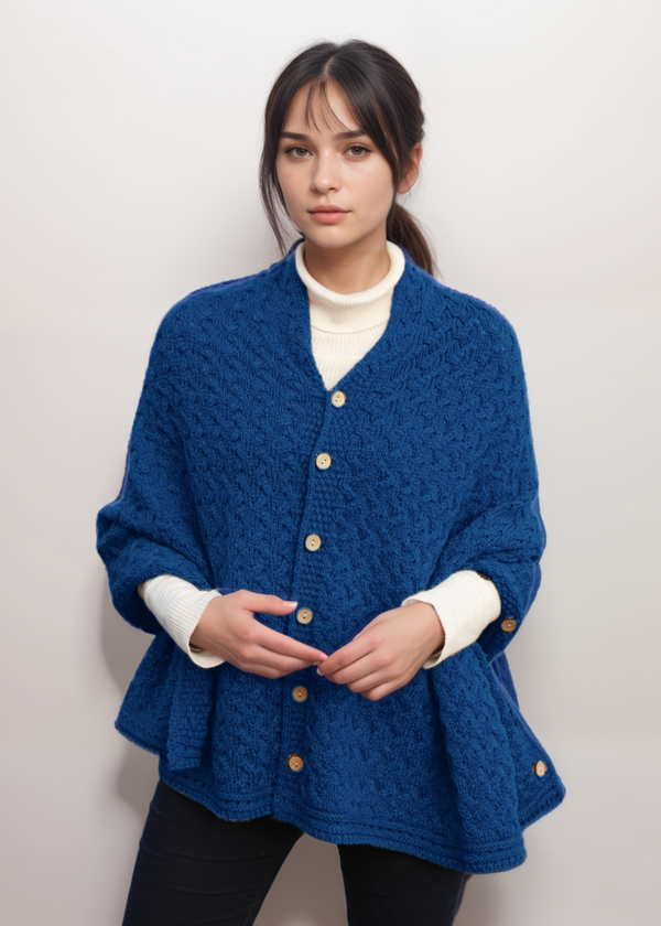 Woman wearing a blue aran knitted cardigan with a plain background