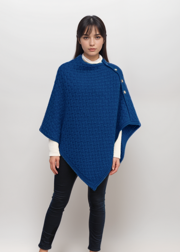 Woman wearing a blue aran poncho on a white background
