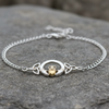 Silver bracelet with claddagh design on a stone surface