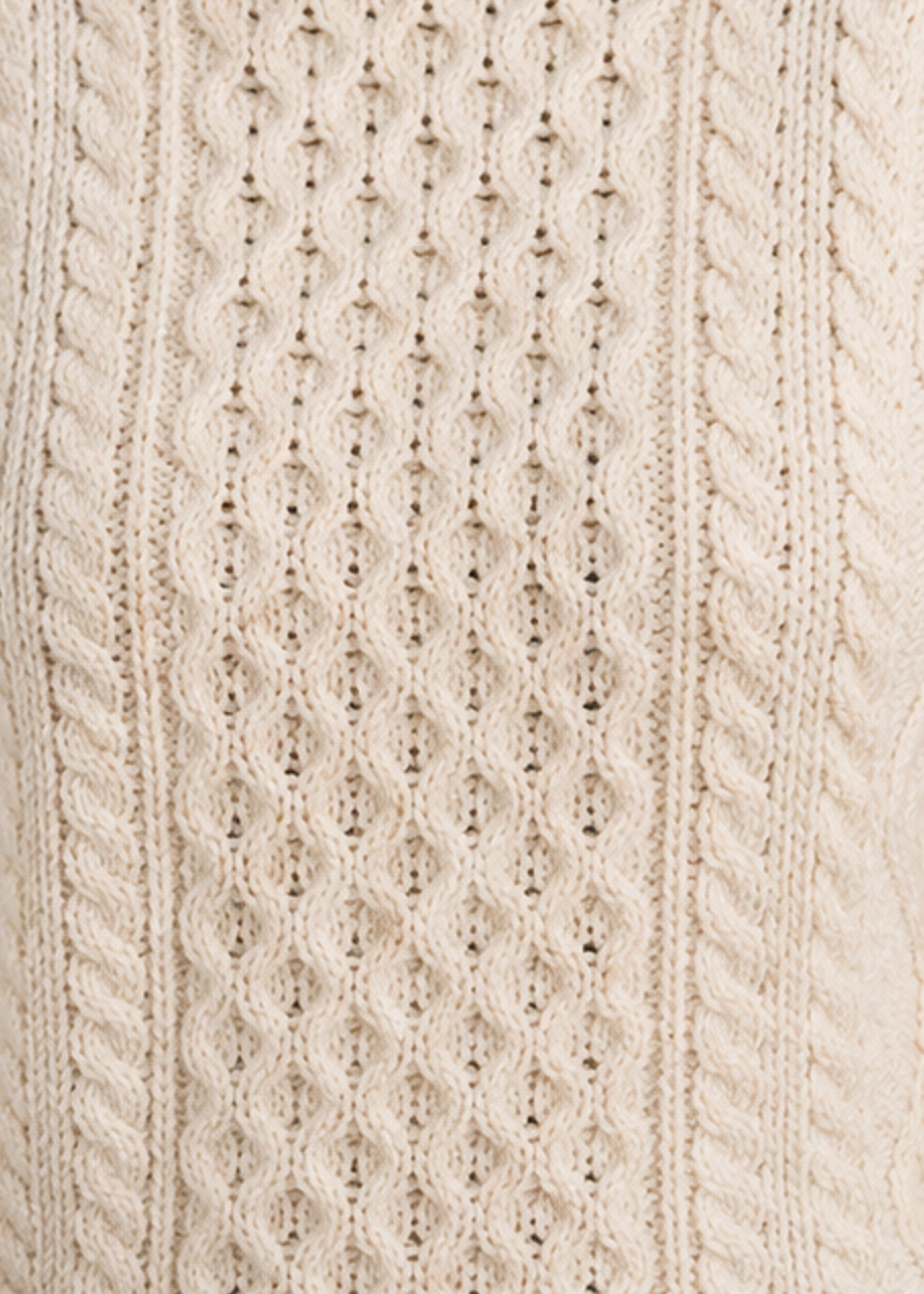 Close-up of a cream-colored knitted fabric with cable pattern