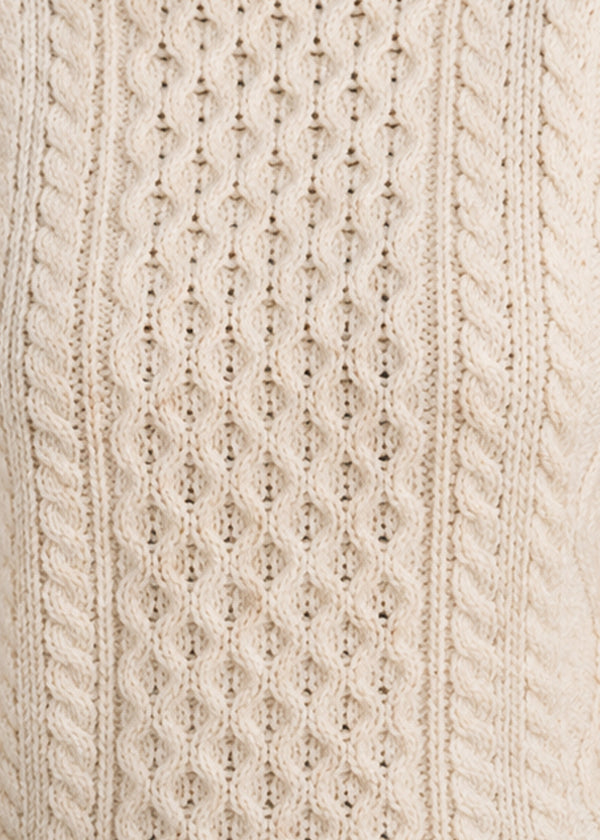 Close-up of a cream-colored knitted fabric with cable pattern