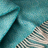 Close-up of a teal and gray textured fabric with a fringed edge