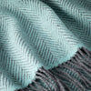 Close-up of a teal and gray herringbone patterned scarf with fringes.
