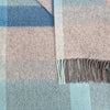 Close-up of a plaid fabric with blue, pink, and gray colors.