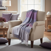 Beige armchair with a purple and gray striped blanket in a living room setting.