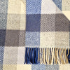 Close-up of a checkered fabric with blue, beige, and gray colors and fringed edges.
