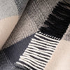 Close-up of a textured fabric with a herringbone pattern and fringed edge.