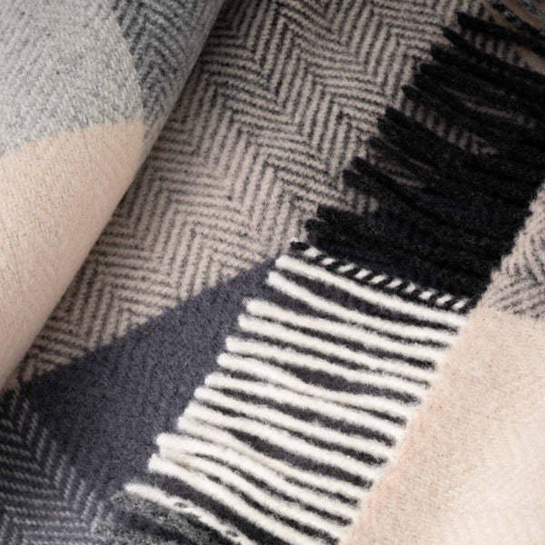 Close-up of a textured fabric with a herringbone pattern and fringed edge.