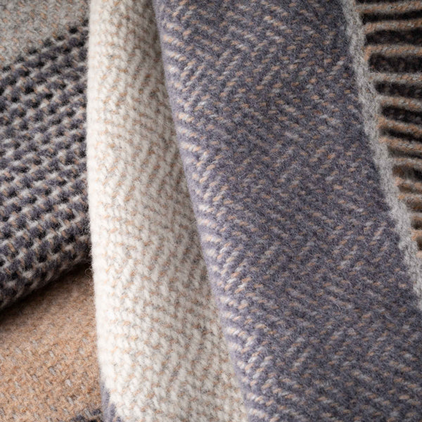 Close-up of textured fabric with a herringbone pattern in shades of gray and beige.