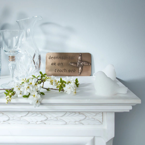 Decorative plaque with a cross on a white surface with flowers and a vase.